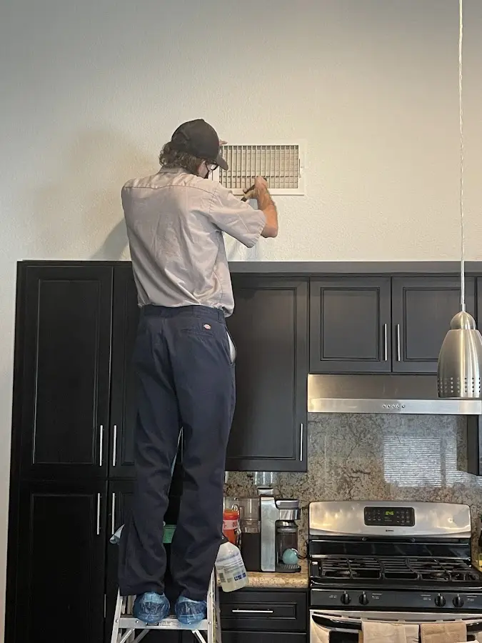 Technician inspecting an air vent during HVAC service in Clifton Park